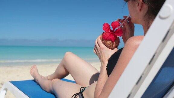 古巴在沙滩上喝着饮料坐在椅子上放松的女人