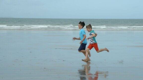 两个男孩在沙滩上玩慢镜头跑步比赛