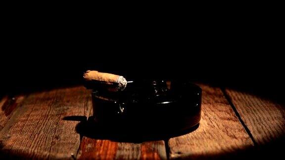 雪茄放在一张木桌上的烟灰缸里被聚光灯照亮的