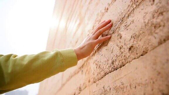 女人的手触摸着旧墙