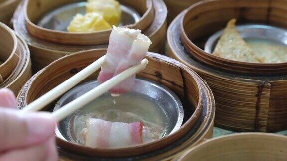 手用筷子吃传统的中国食物新鲜美味美味美味的蒸肉点心在餐厅的竹篮