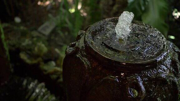 慢镜头水缸喷泉在绿色花园