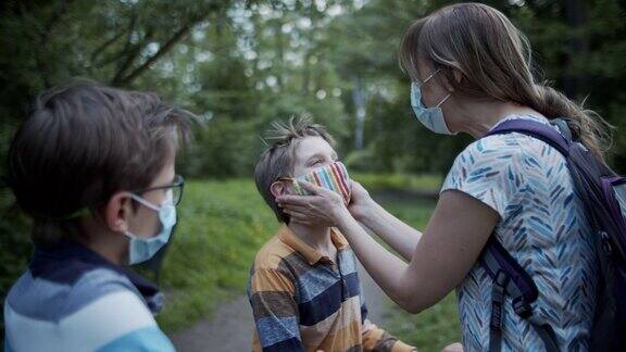 COVID-19大流行期间母亲正在帮助儿童在公园调整口罩