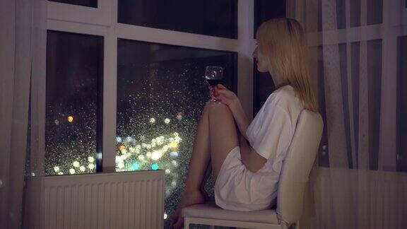 在夜色的城市背景下一个女人拿着一杯葡萄酒