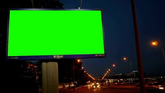 一个在繁忙的夜晚街道上的绿屏广告牌