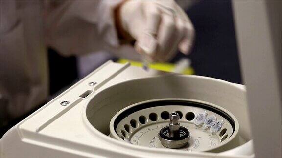 封闭的女科学家装载小瓶液体到一个实验室的离心机