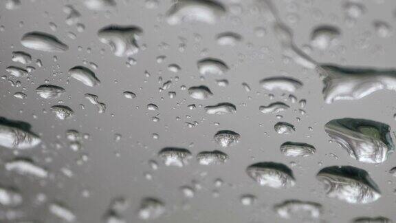 水滴落在车窗玻璃上雨滴落在蓝色的窗户上雨点落在雨天下雨慢镜头特写