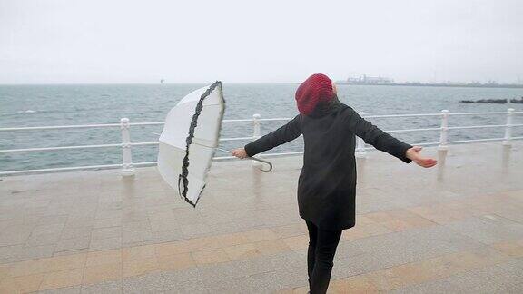 一个欢快的年轻女子在雨天撑着伞跳舞