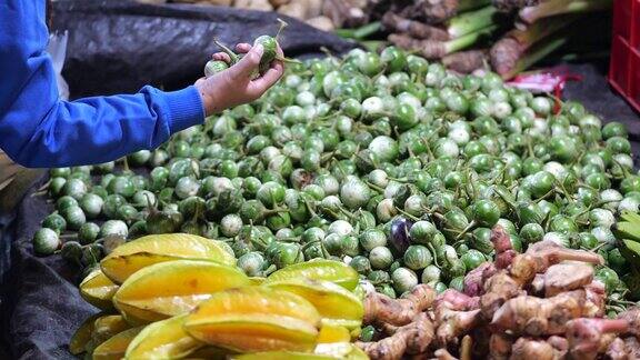 一名印尼妇女在传统的菜市场挑选蔬菜在当地市场购物概念
