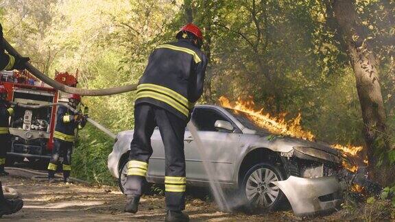 匿名消防员正在扑灭树旁汽车上的大火