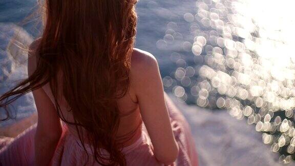 红发女郎坐在岩石上望着大海