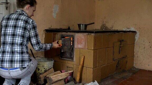 女孩把木头放在农舍厨房里的旧土制粘土炉里4k