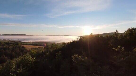 在晨雾中飞过薄雾的森林在日出时阳光照射在树梢航拍在fpv无人机云朵自然景观与山地丘陵地形电影的看法