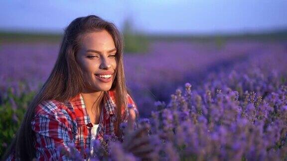 女孩的手抚摸着嗅着田野里紫色的薰衣草花