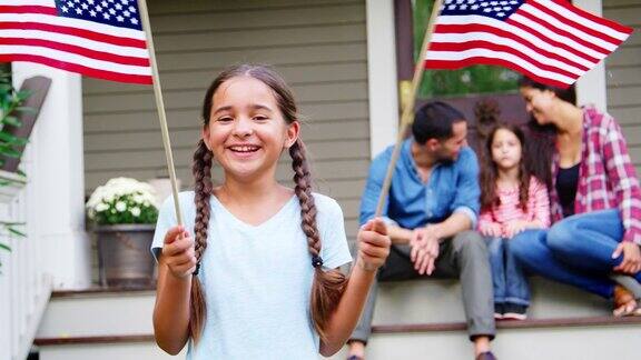 和家人在屋外举着美国国旗的女孩