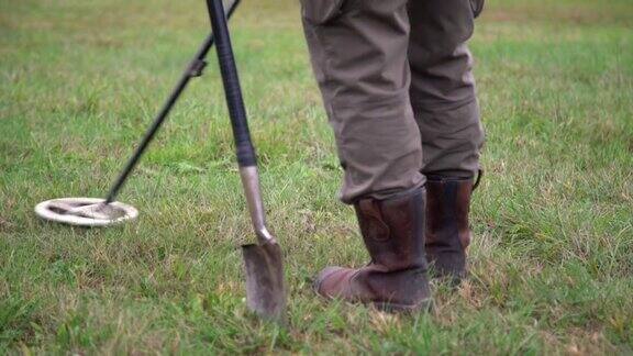 穿着靴子的人在草地上用金属探测器寻宝一名男子在地下寻找硬币