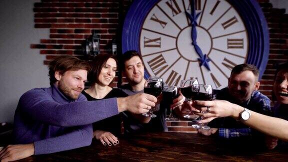 五个老朋友在餐厅庆祝结婚纪念日举杯畅饮人们坐在桌旁举起酒杯一起敬酒
