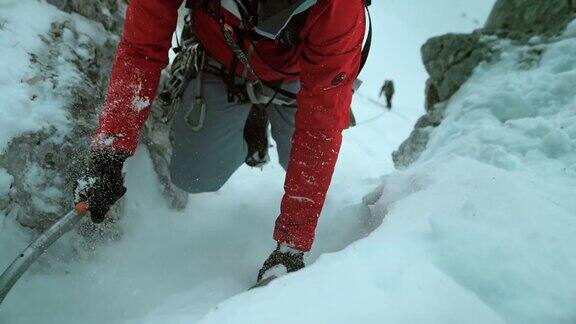 冬季登山者用斧头攀登积雪覆盖的斜坡