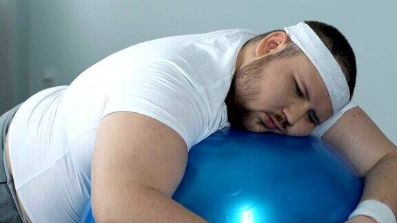 懒惰的胖子在健身球上放松缺乏运动动力徒劳无功