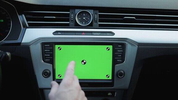 年轻男子使用导航应用程序的特写在安装模型绿色屏幕内的现代汽车一名男子驾驶着一辆装有绿屏智能手机导航的汽车在街上行驶