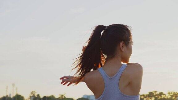 新常态的户外运动年轻的亚洲健身运动女性伸展她的身体在户外锻炼前热身为了健康和幸福穿着运动服的女孩在黄昏时分在户外锻炼