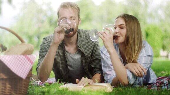 特写镜头情侣在公园里浪漫的野餐喝红酒