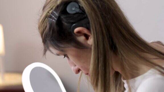 年轻女子在家用人工耳蜗化妆