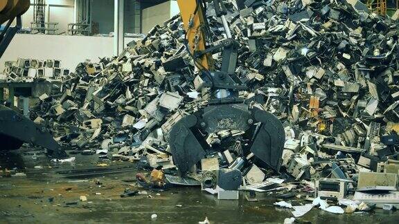 电子垃圾回收工厂装载机抓住了有缺陷的电子元件碎片