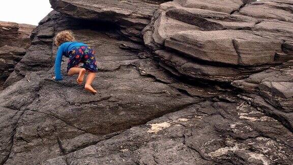 蹒跚学步的孩子爬上岩石巨石的大自然