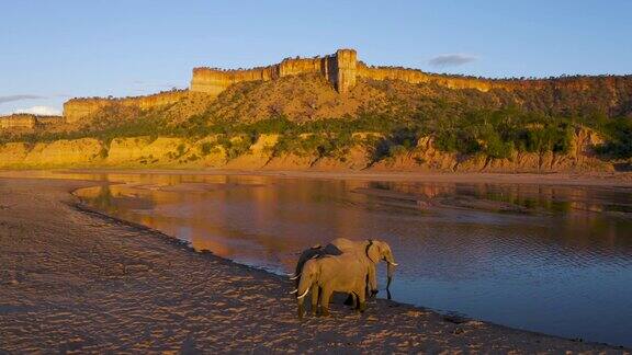 津巴布韦戈纳雷州国家公园阳光照在美丽的红色砂岩奇洛霍悬崖上大象在下面的Runde河中饮水和沐浴尘土