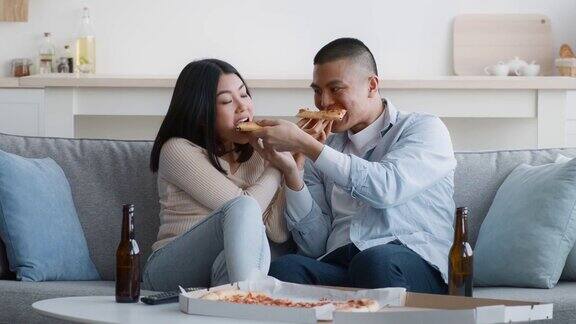 亚洲夫妇吃披萨在家喂对方