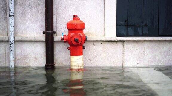 洪水淹没了城市街道鲜红色的消防栓