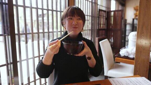 年轻女子在日本餐馆吃“DonabeGohan”健康的日本食物