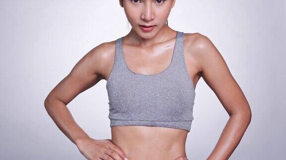 年轻的亚洲女人在白色的背景看袖子和腰部自己的锻炼和饮食控制