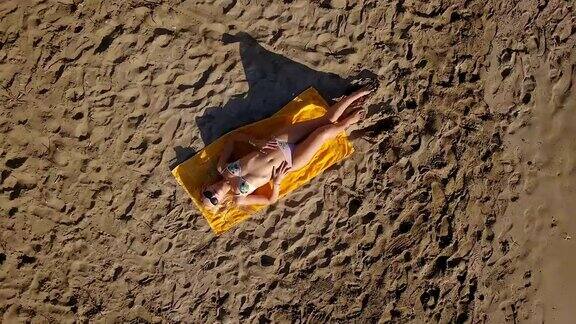 迷人的年轻女孩在海边的海滩上晒太阳