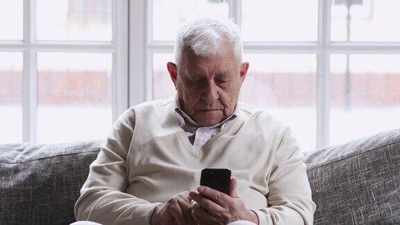 笑容满面的80后老爷爷坐在沙发上用手机应用