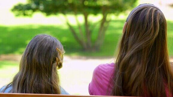 母亲和女儿一起坐在公园的长椅上
