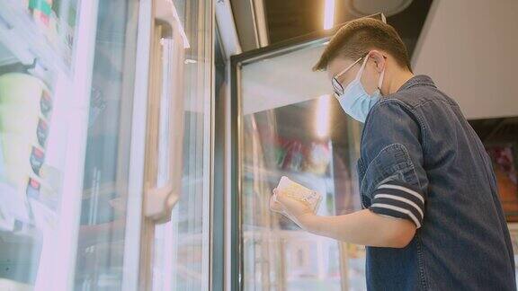 亚洲男性在超市或商店购买食品杂货时戴着防冠状病毒的医用口罩健康、安全和大流行在隔离期间购物