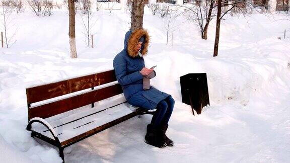 女人正坐在长椅上浏览手机