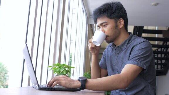 一个亚洲人在咖啡馆用笔记本电脑工作