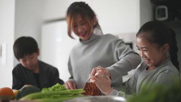 亚洲中国母亲和女儿儿子在厨房里切碎胡萝卜准备凉拌卷心菜沙拉