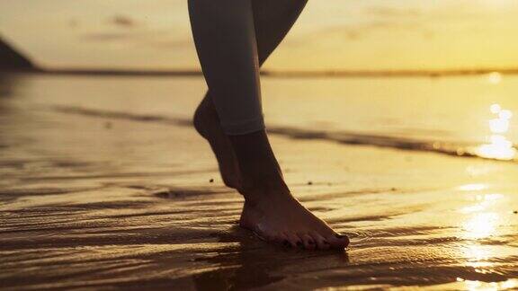 海岸慢跑训练享受日落和自由的女人赤脚走在潮湿的沙滩上