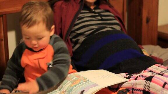 小男孩和怀孕的妈妈在床上看书