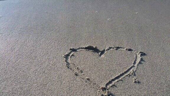 画在沙滩上的心的形状被轻柔的海浪冲走海上度假一个爱情故事和一个浪漫的假期