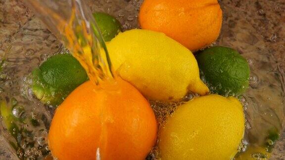 水果清洗过程一股水流落在玻璃碗里的柑橘类水果、橙子、柠檬和酸橙上缓慢的运动