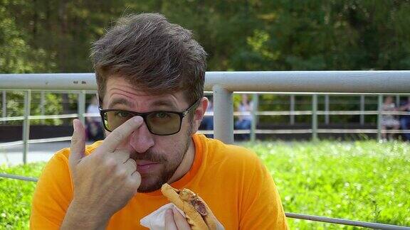 一个戴眼镜留着胡子的中年男人正在吃热狗特写镜头