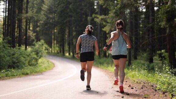 女运动员在森林道路上奔跑的后视图