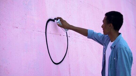 惊恐的少年用喷漆在墙上画和平符号阻止种族主义