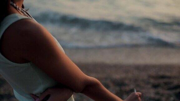 日落时分一个女孩在海边抽着烟