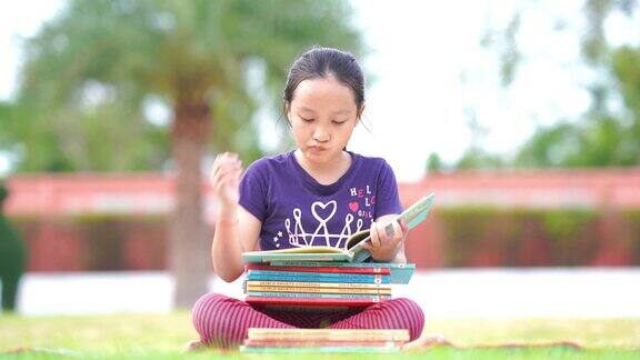 亚洲女孩在花园里看书思考认真